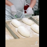 Costco Baker Doesn't Miss A Beat While Slicing Up The Country French Bread